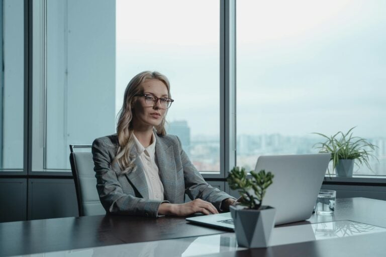 Confident businesswoman in grey suit working on laptop in modern office