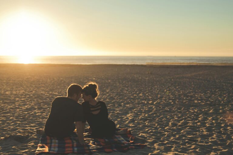 Couple enjoys sunset together on sandy beach capturing moment of love.