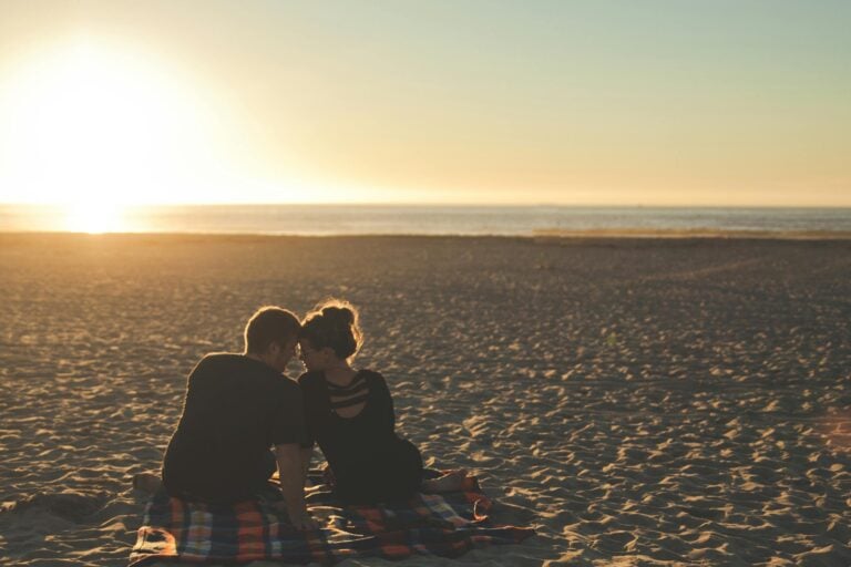 Couple enjoys sunset together on sandy beach capturing moment of love.