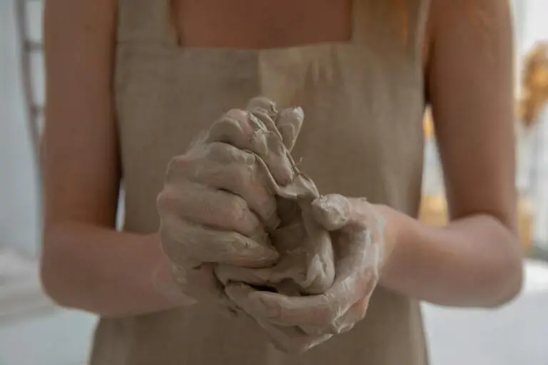 Craftswoman kneading clay in indoor workshop showcasing detailed hands-on craftsmanship