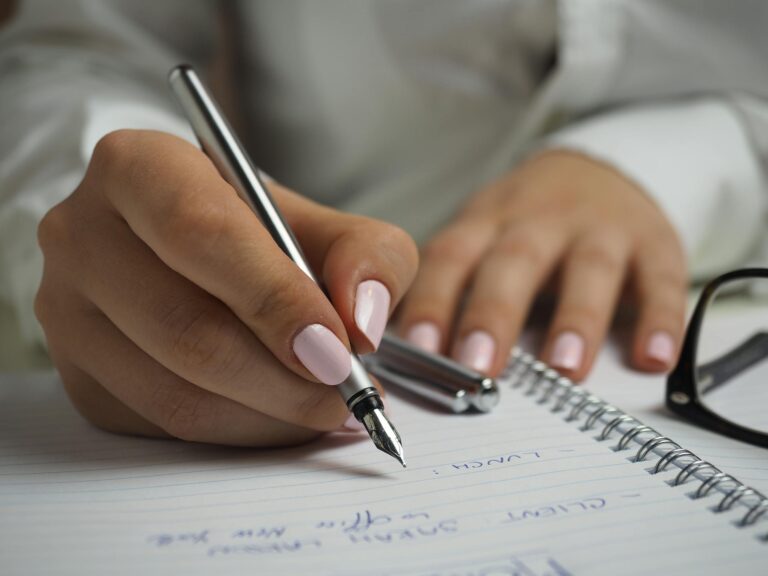 Close-up of handwriting in notebook with fountain pen and glasses