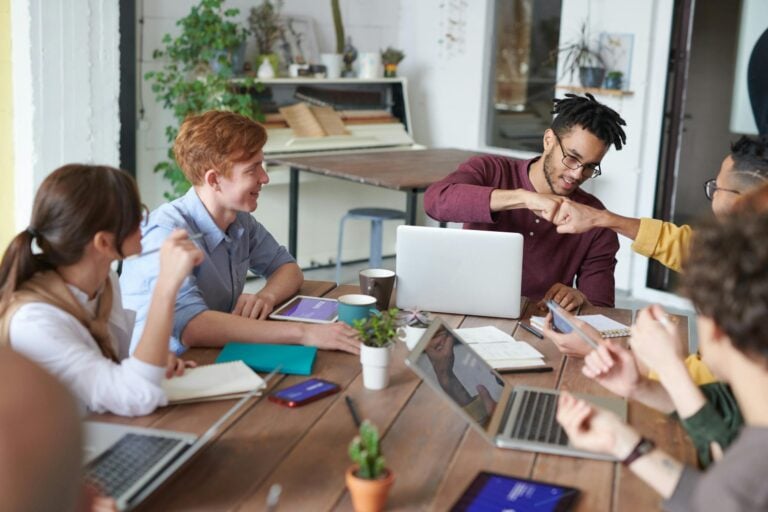 Diverse group of young professionals brainstorming around table in modern office environment.