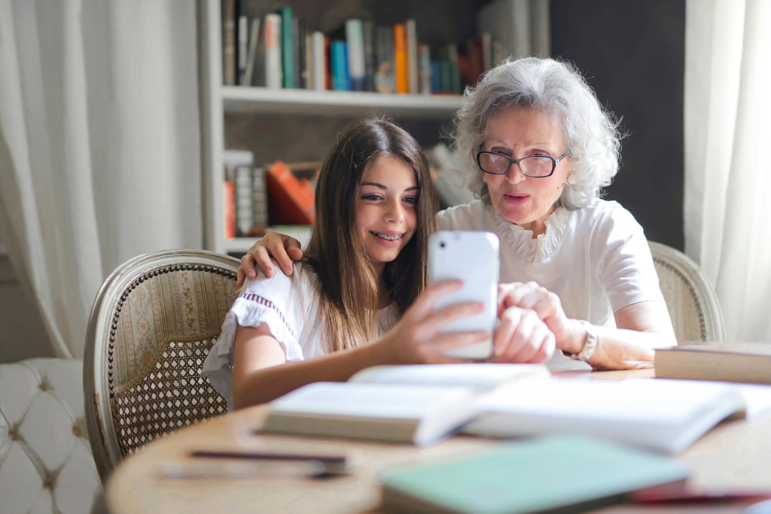 Grandmother and granddaughter bonding over smartphone together at home