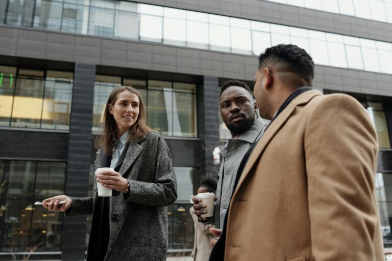 Group of diverse professionals having coffee and discussing business outdoors.