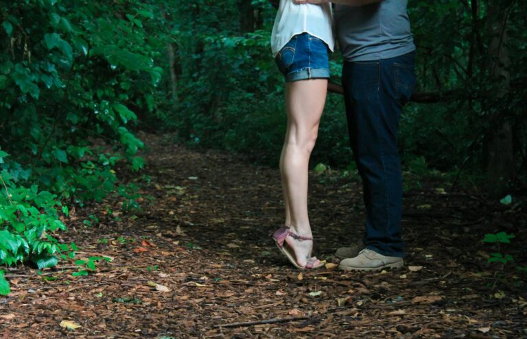 Loving couple embracing on secluded forest pathway surrounded by lush greenery.