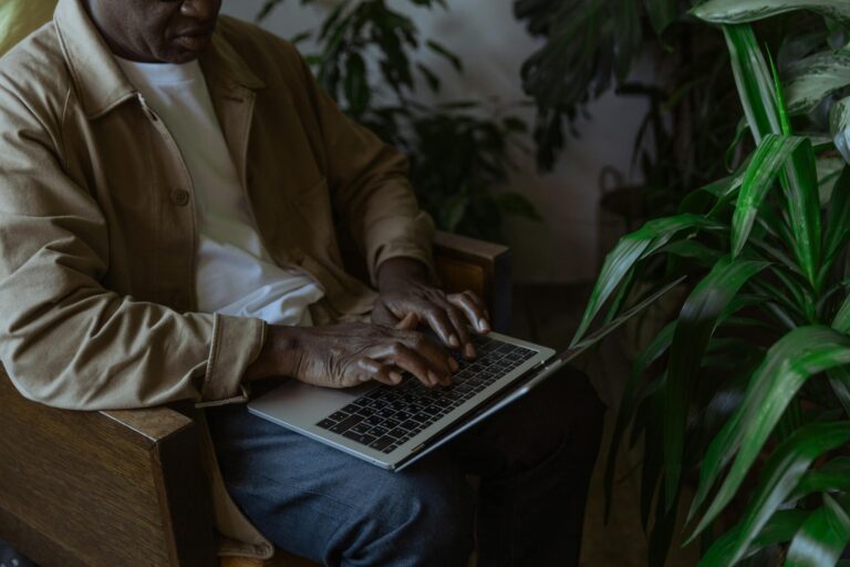Man working on laptop in cozy indoor setting surrounded by lush green plants