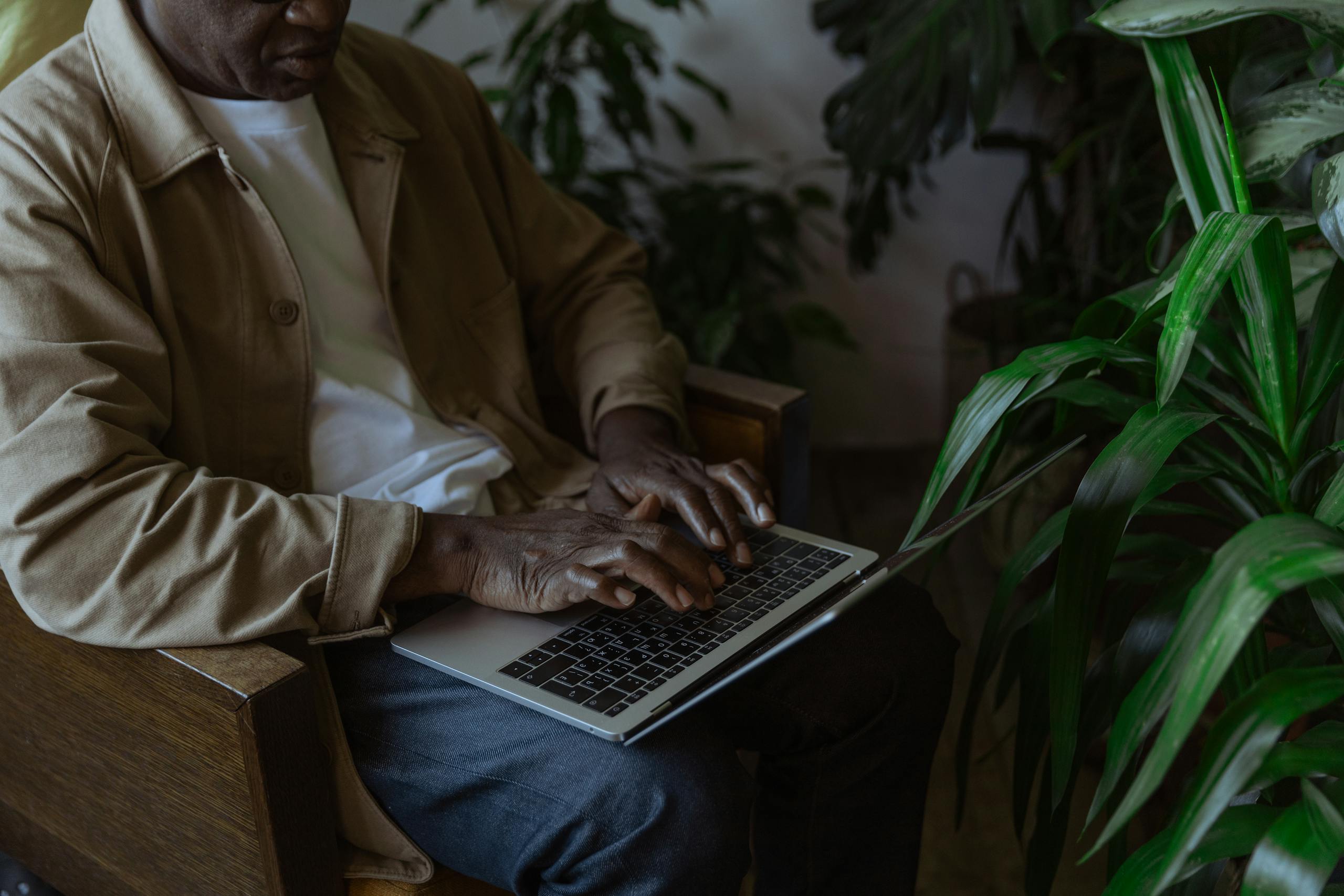 Man working on laptop in cozy indoor setting surrounded by lush green plants