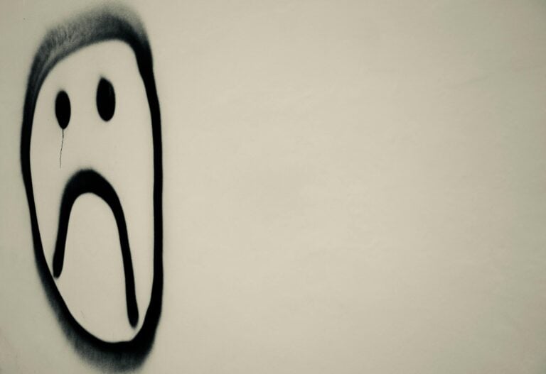 Monochrome graffiti sad face on urban wall expressing emotional melancholy symbolically