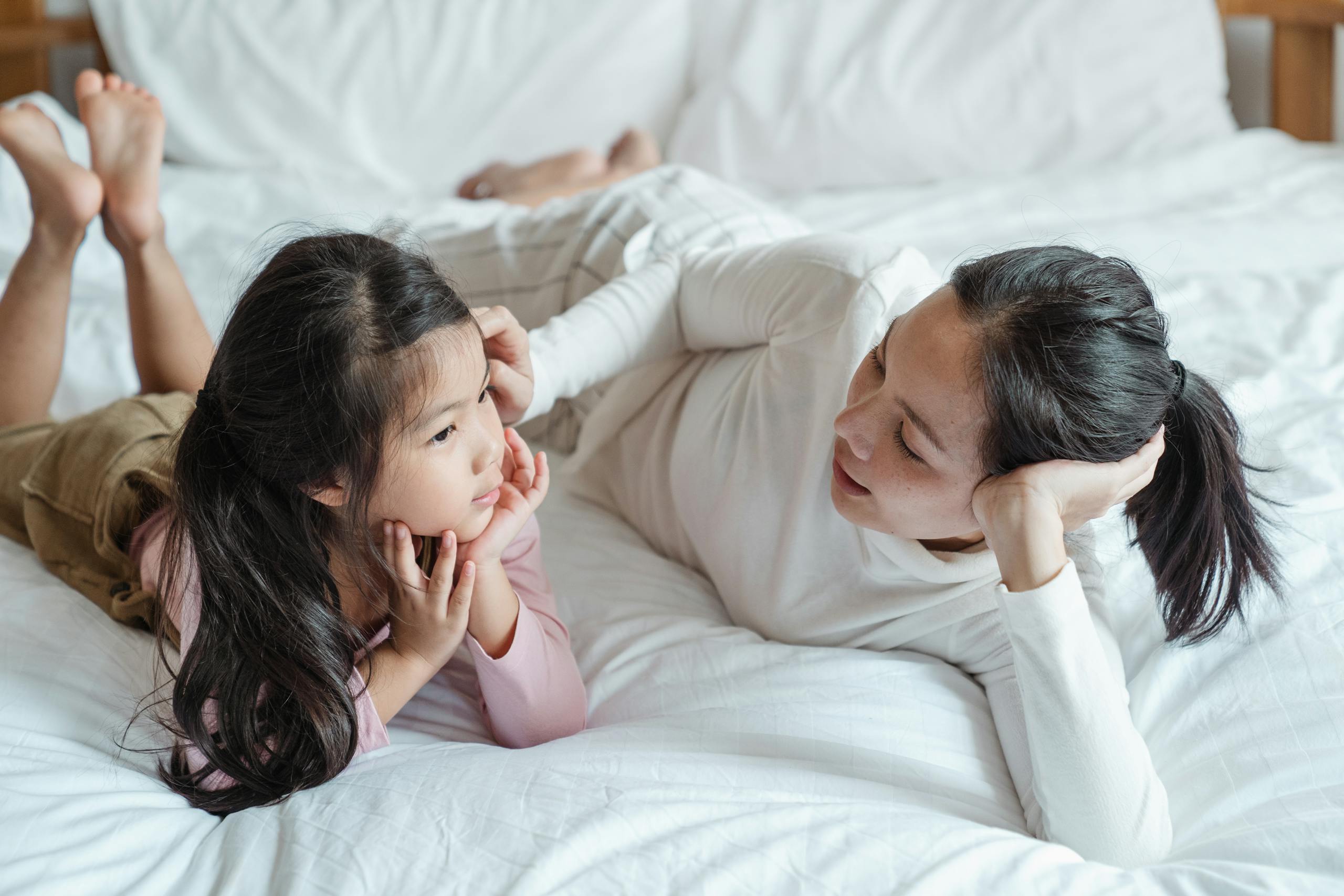 Mother and daughter bonding together lying on bed indoors