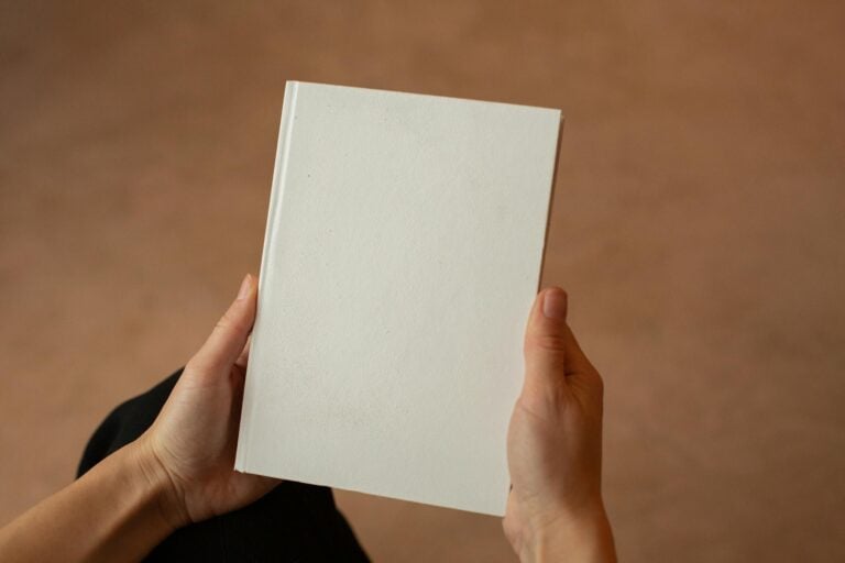 Person holding blank hardcover book with visible empty pages