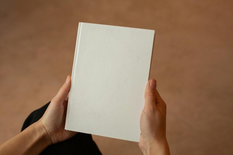 Person holding blank hardcover book with visible empty pages