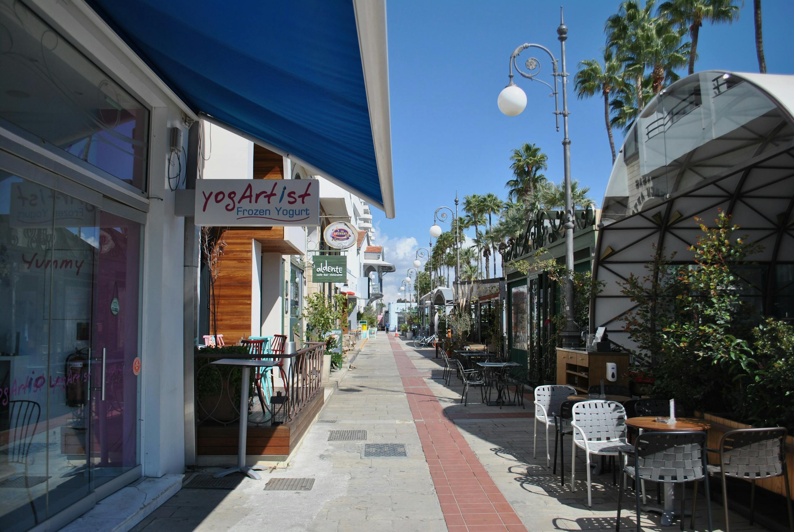 Picturesque street with cafes and palm trees beneath bright blue sky