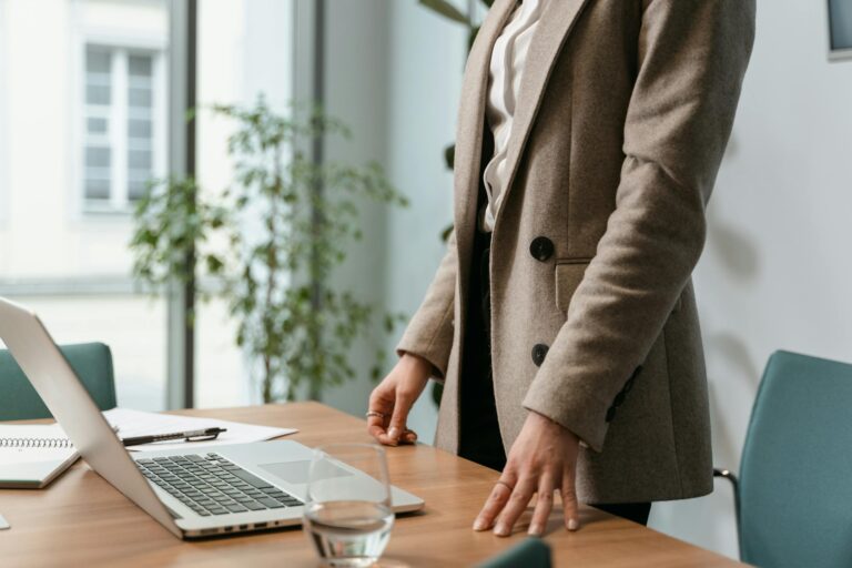 Professional businesswoman in stylish office environment with laptop and notes.