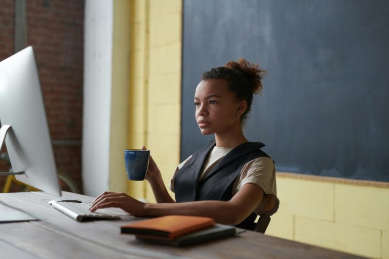 Professional young woman concentrating on work at desk with computer and coffee
