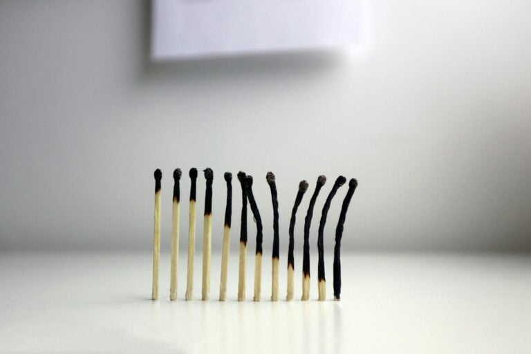 Row of burnt matches against neutral background representing burnout and exhaustion conceptually.