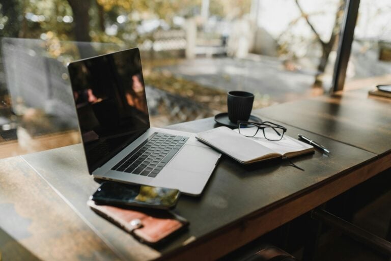 Serene office workspace with laptop, notebook, coffee near autumn window