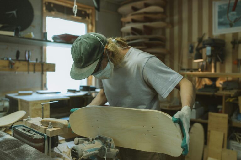 Skilled craftsman using router to shape skateboard deck in workshop setting.