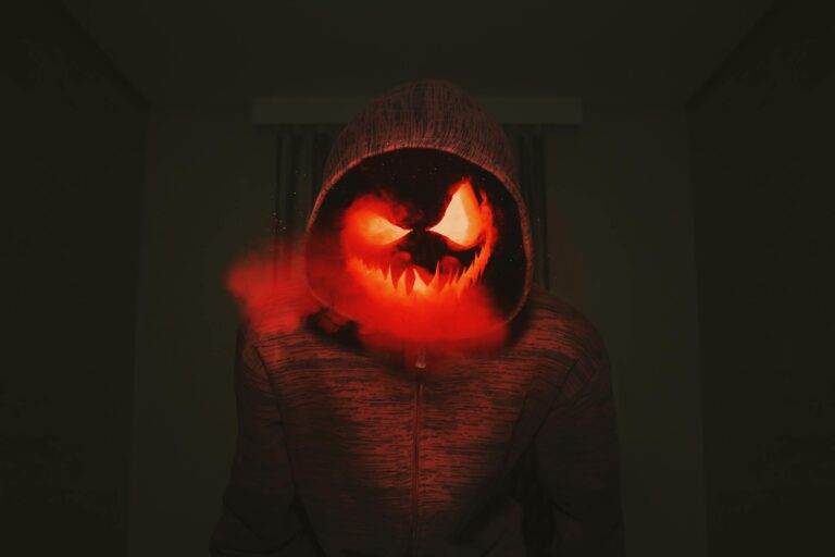 Spooky pumpkin head in hoodie exuding creepy Halloween vibe with red smoke.