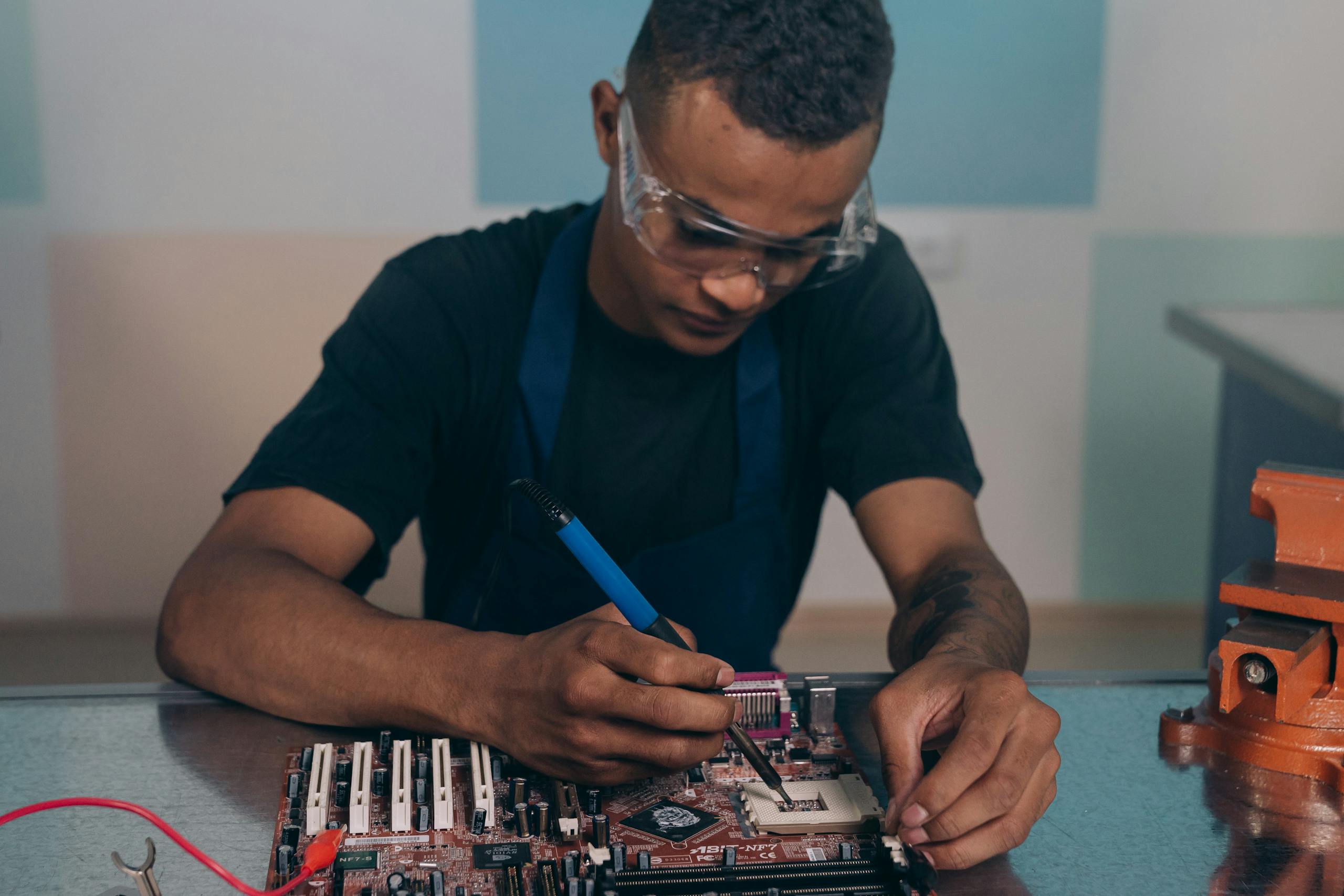 Technician wearing safety glasses working intently on computer motherboard