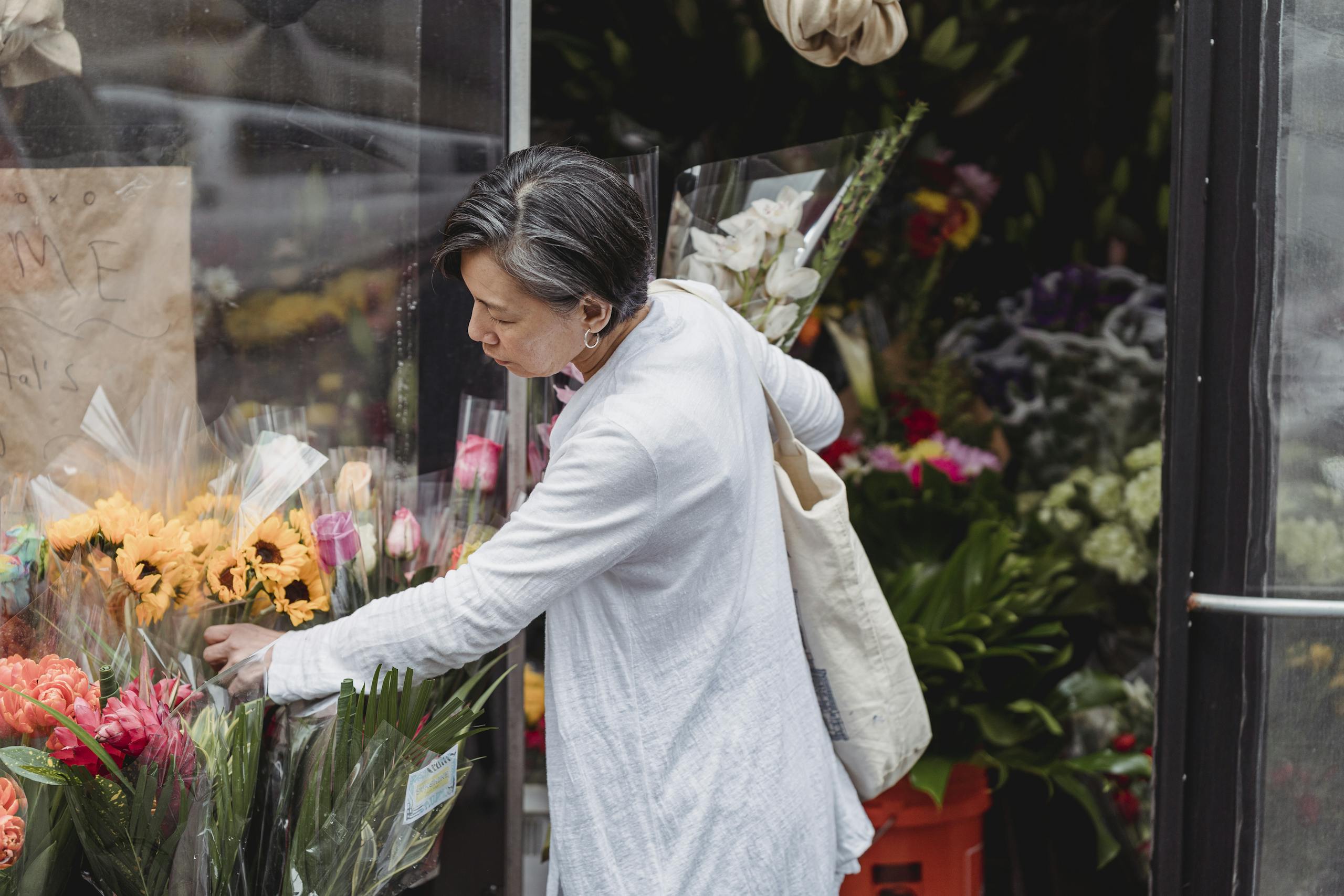 Woman carefully selecting flowers from outdoor florist stand