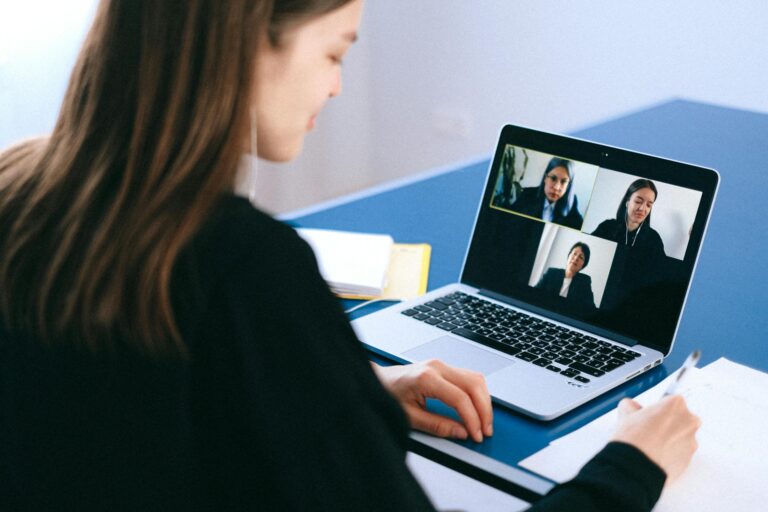 Woman engaging in video conference using laptop at home taking notes