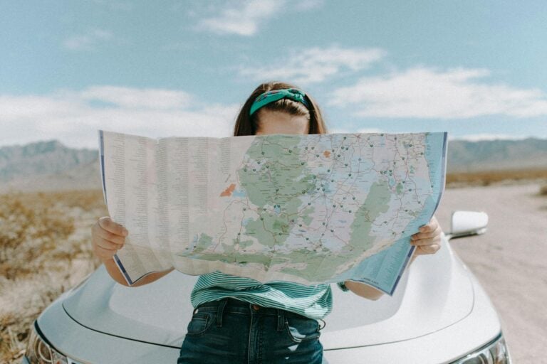 Woman holding map while traveling through scenic California desert.