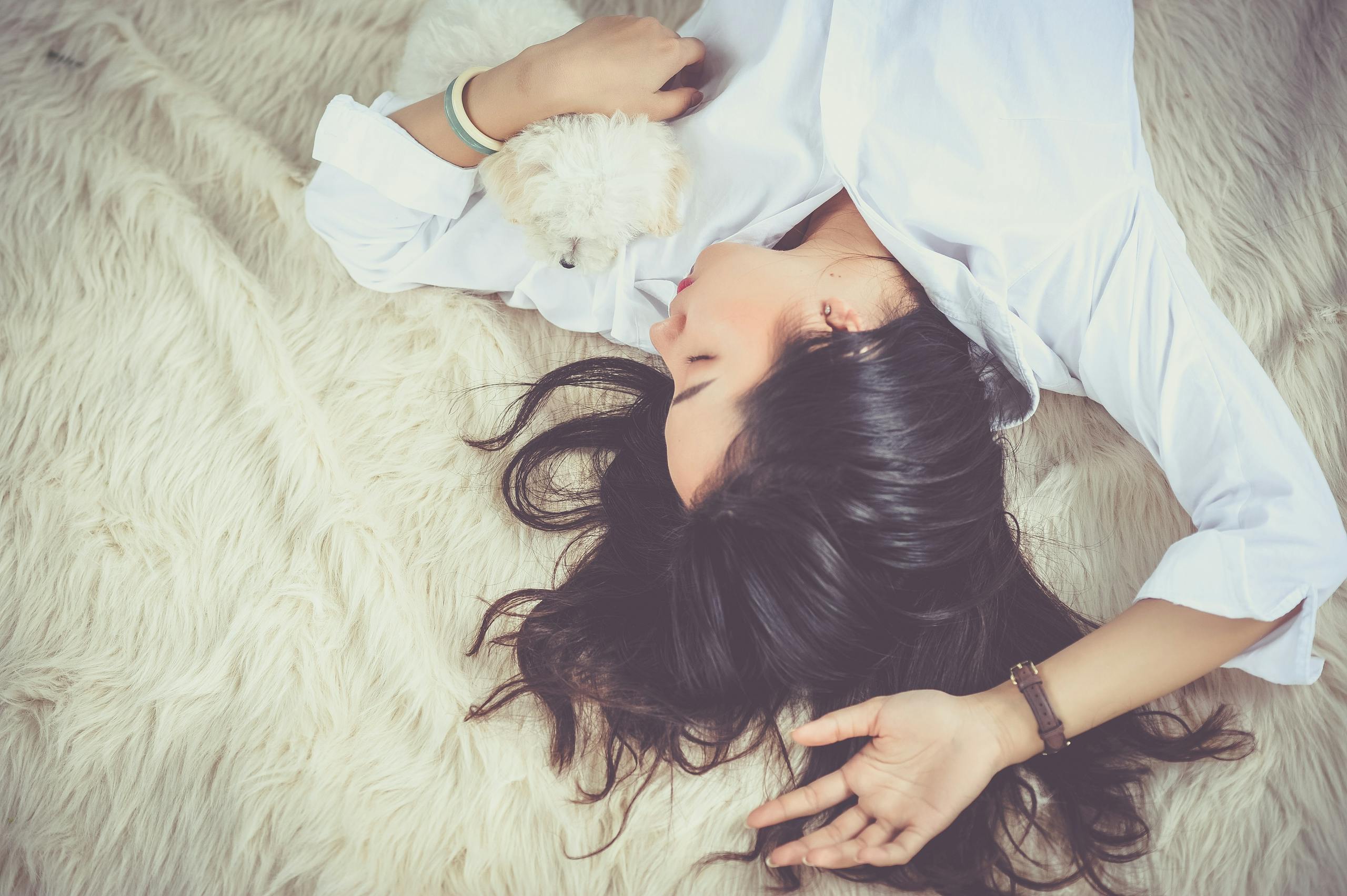 Woman peacefully sleeping with pet dog on soft furry rug
