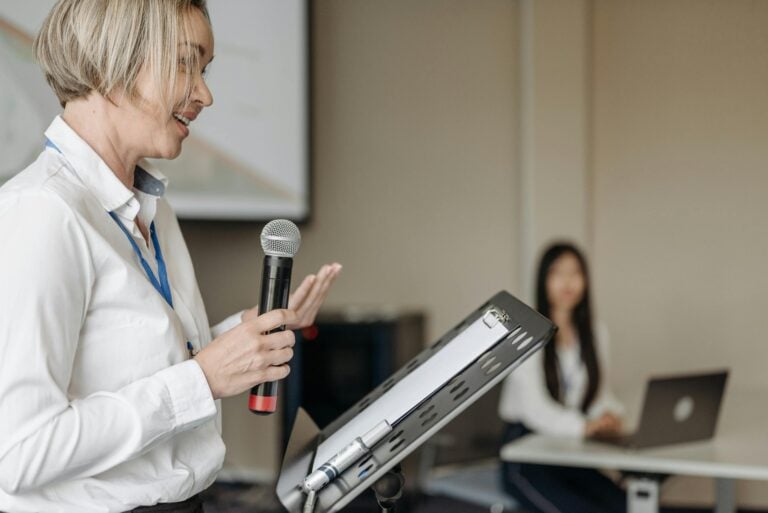 Woman presenting with microphone at professional seminar in front of audience