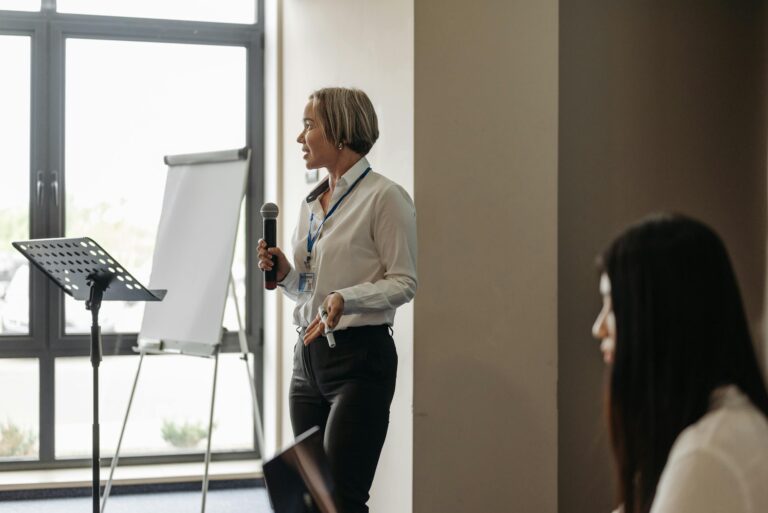 Woman presenting with microphone and flipchart in conference room to audience