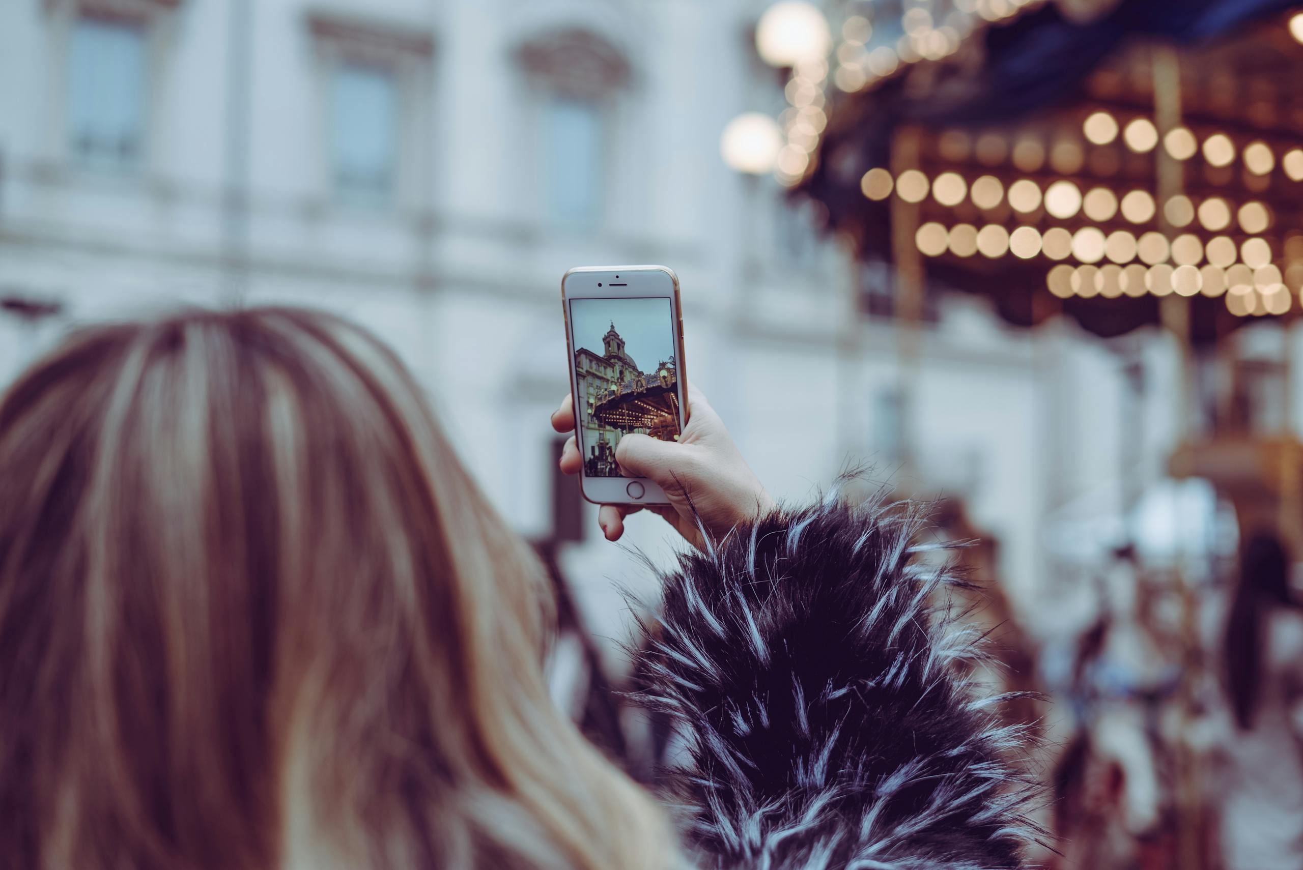 Woman photographing Rome plaza with smartphone during daytime.