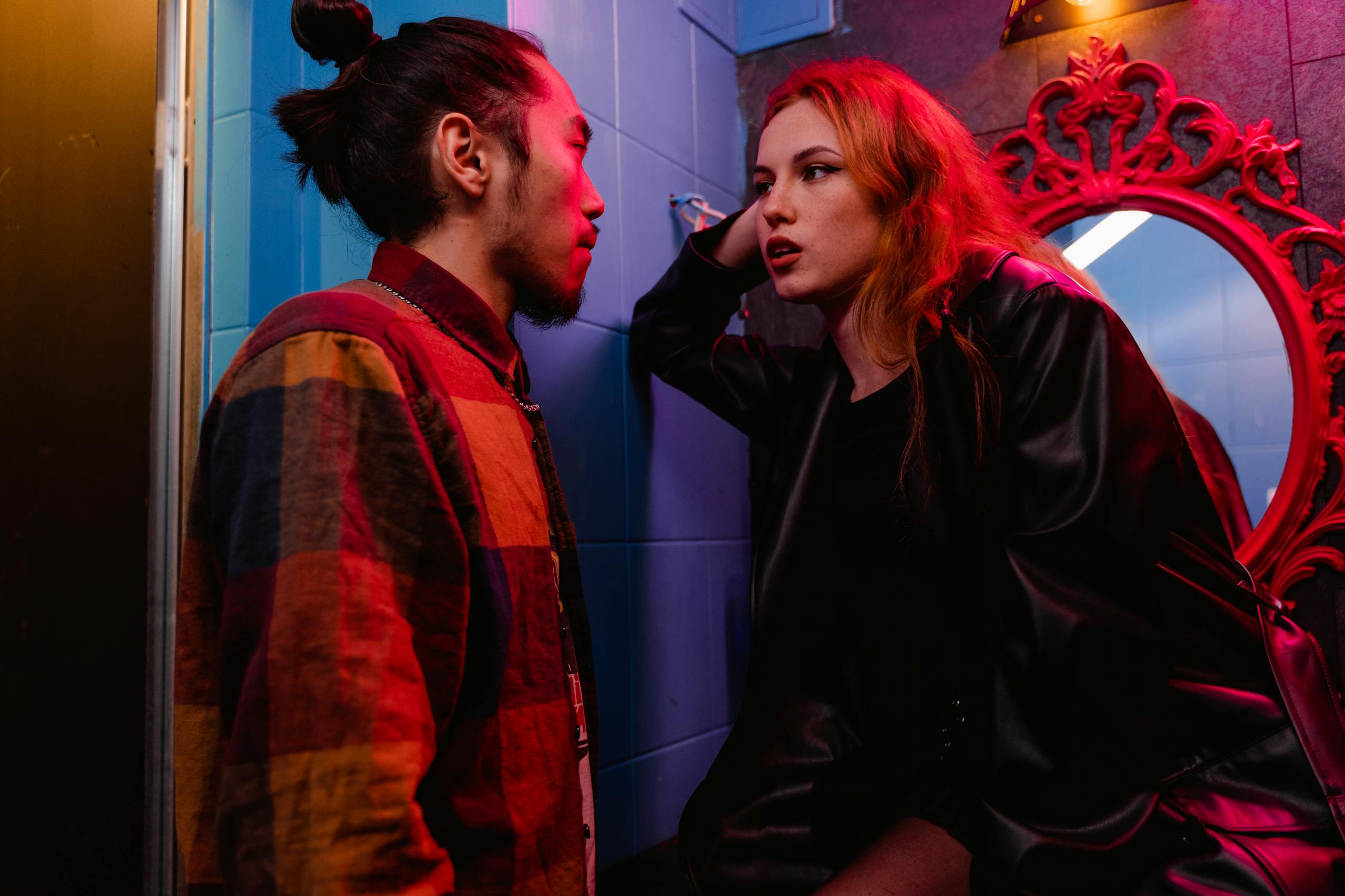 Young couple engaged in deep conversation in dimly lit room with vibrant decor.