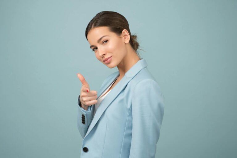 Young woman in blue suit projecting confidence with relaxed pose against blue.