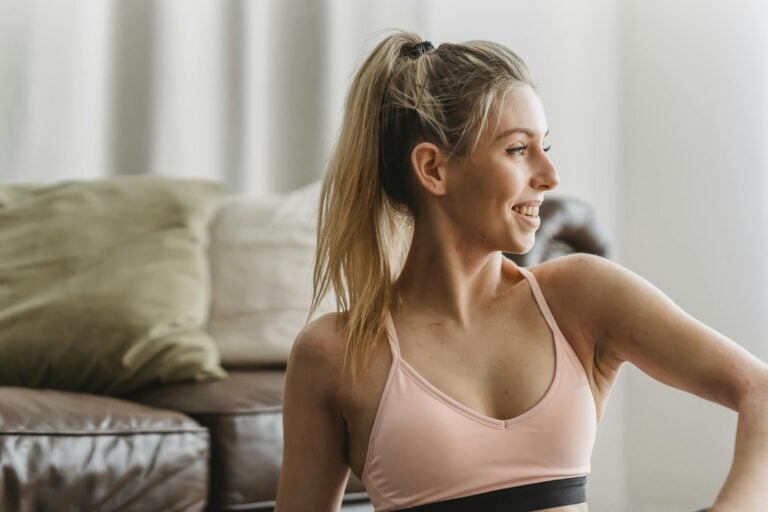 Young woman in activewear smiling confidently while practicing yoga indoors embodying wellbeing