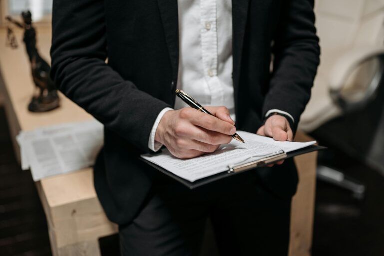 Business professional signing contract on clipboard at office desk with pen
