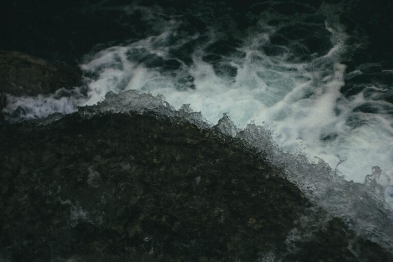 Captivating view of ocean waves crashing against dark rocks showcasing natures raw power