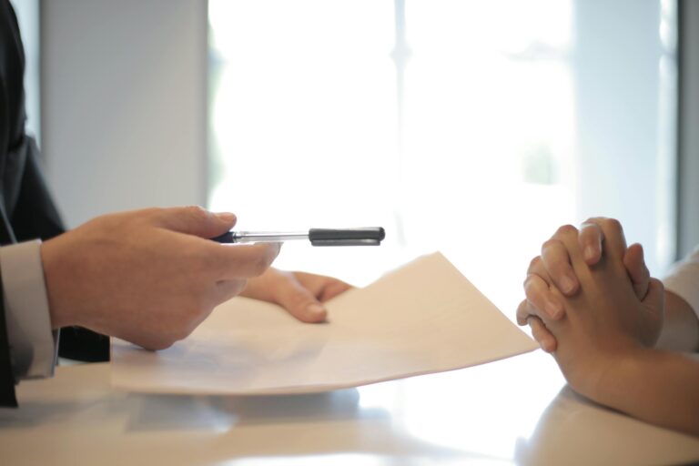 Close-up of contract signing with hands over documents in professional business interaction