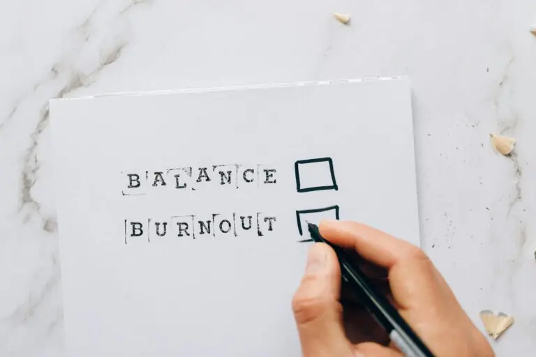 Hand hovering over checklist with balance or burnout options symbolizing stress and choice