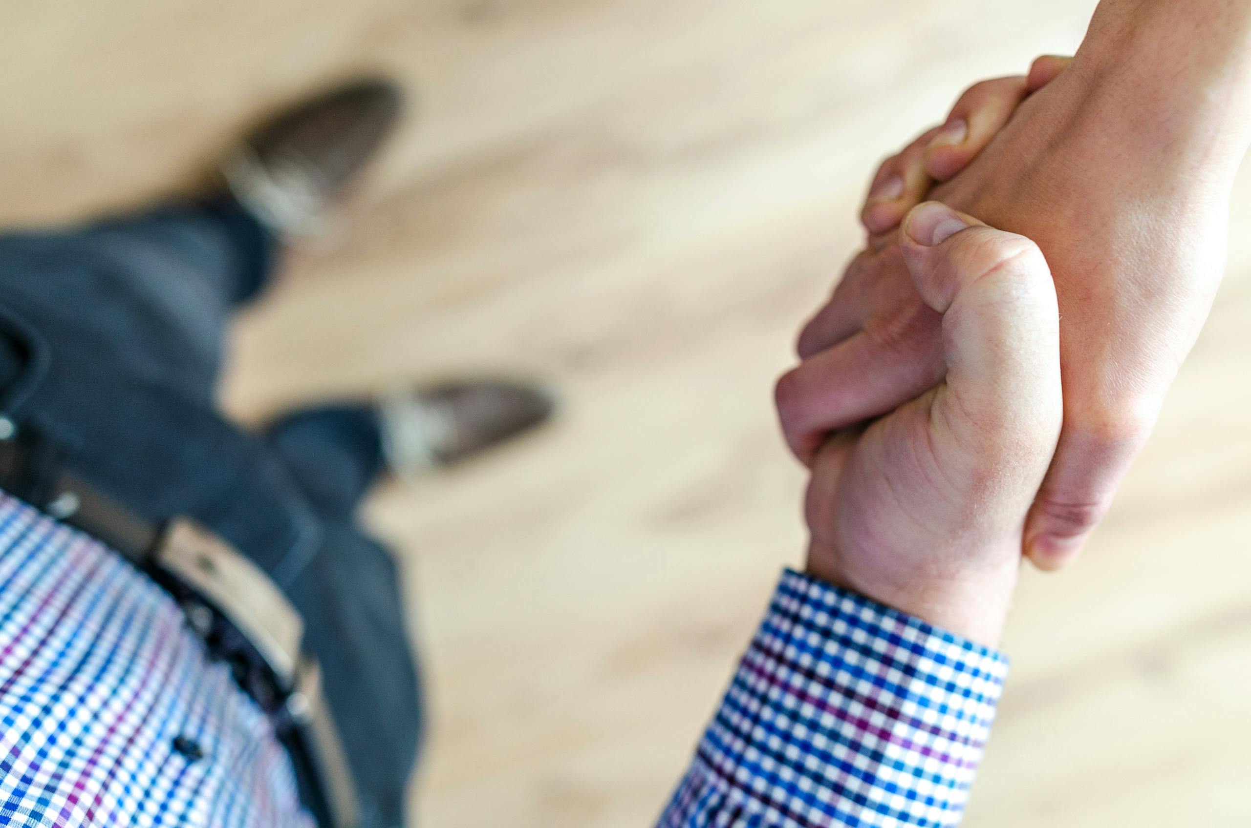 Close-up of handshake between two people inside office symbolizing trust and cooperation.
