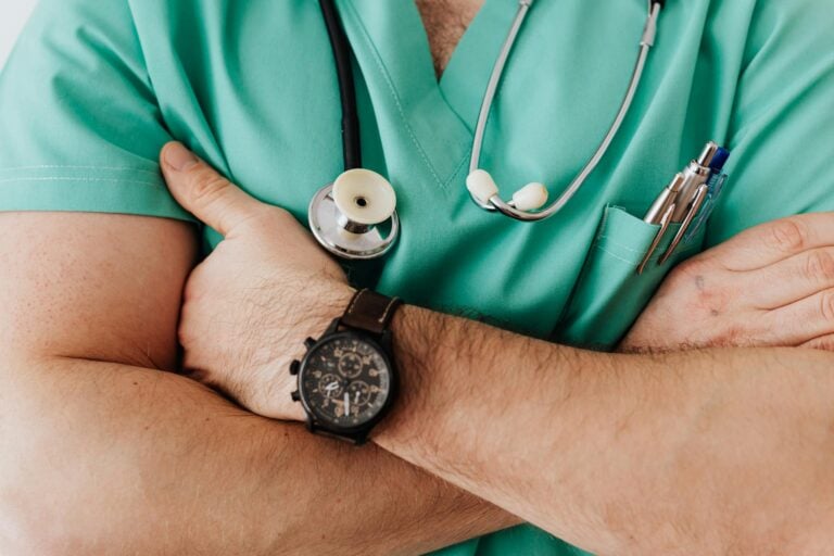 Close-up of confident healthcare professional with crossed arms wearing scrubs and stethoscope