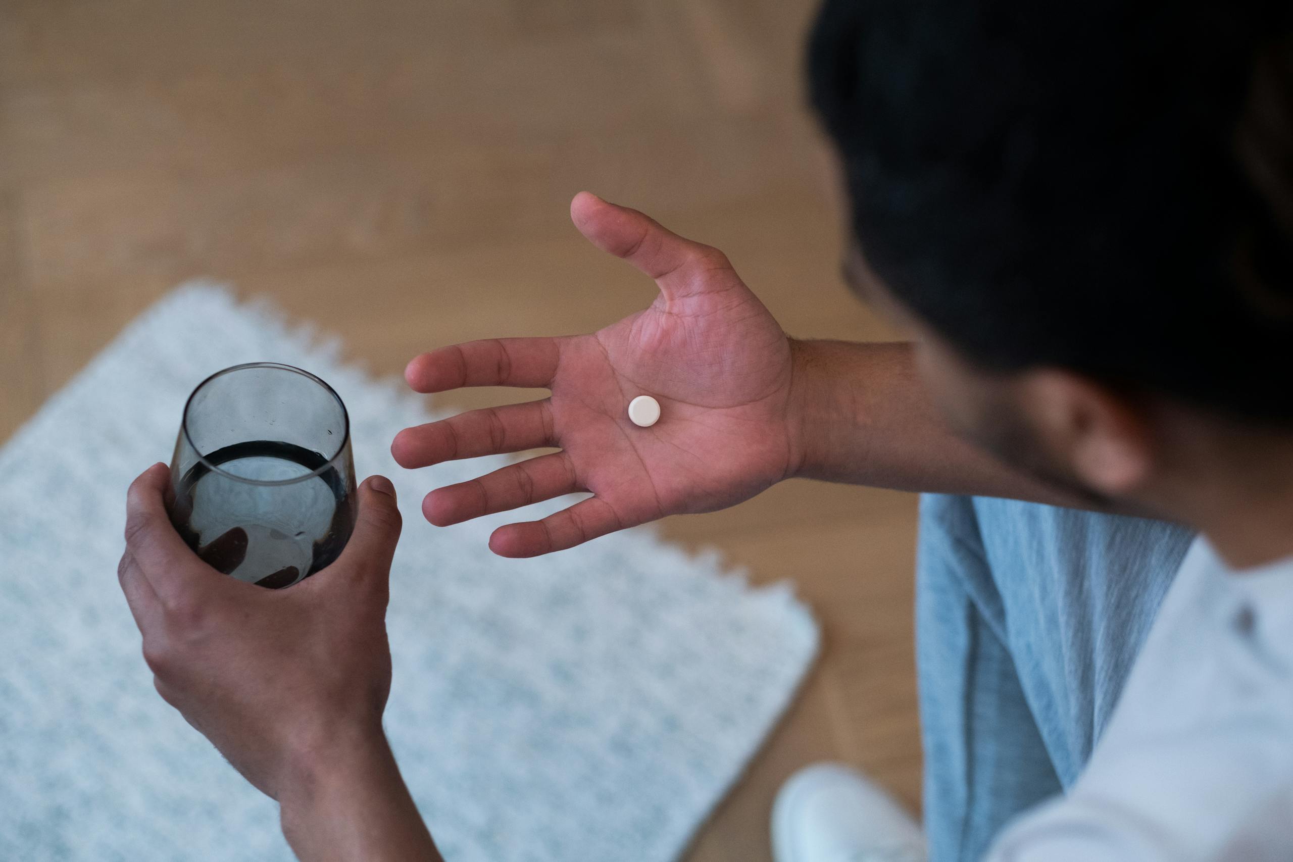 Man about to take medication with water glass indoors