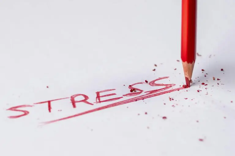 Close-up of red pencil writing stress on paper symbolizing pressure.