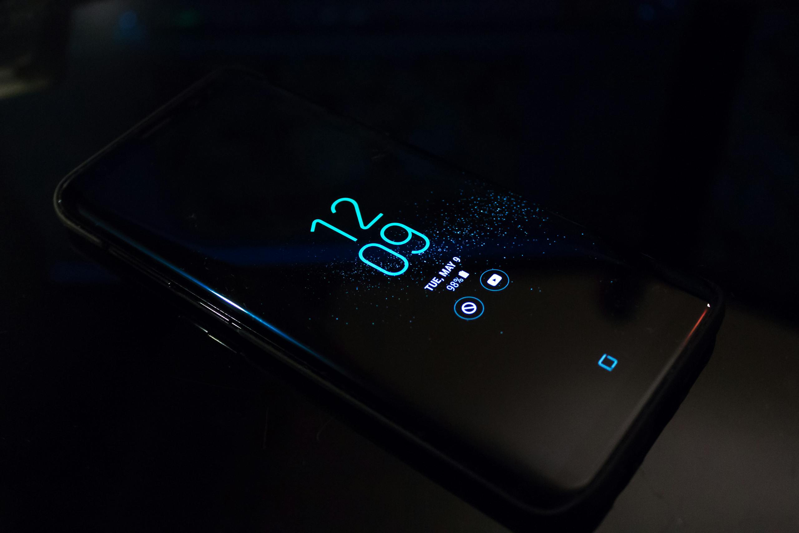 Smartphone in darkness displaying digital clock and notifications.