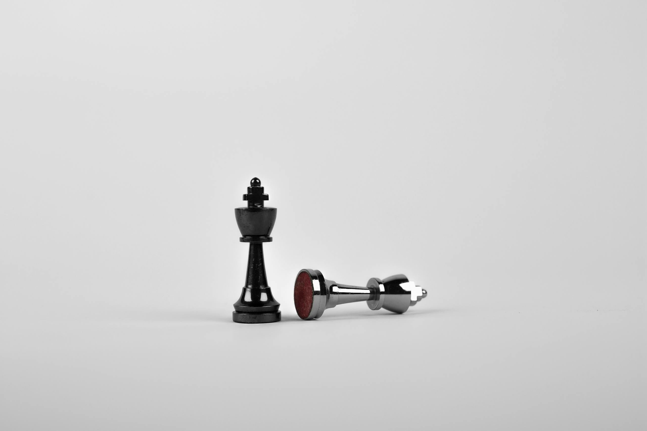Chess king piece standing with fallen piece symbolizing strategy and victory.