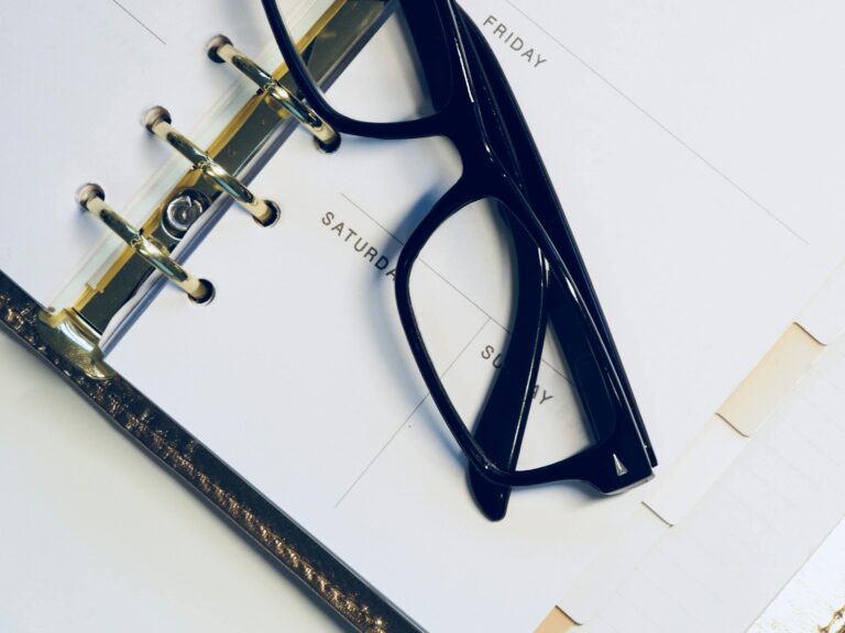Close-up of eyeglasses resting on open planner highlighting the weekend.