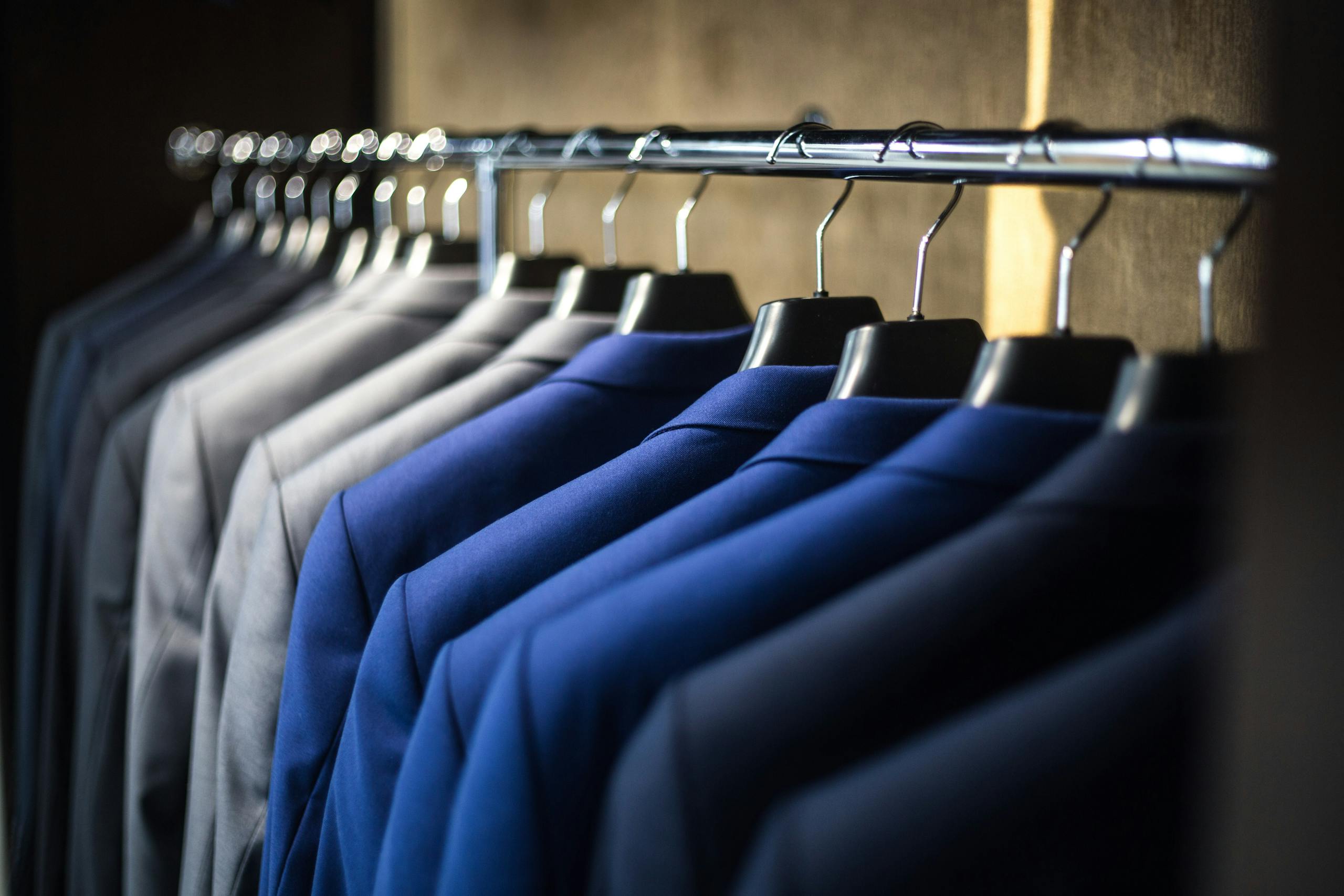 close up of neatly arranged suits in a wardrobe showcasing fashion and organization.