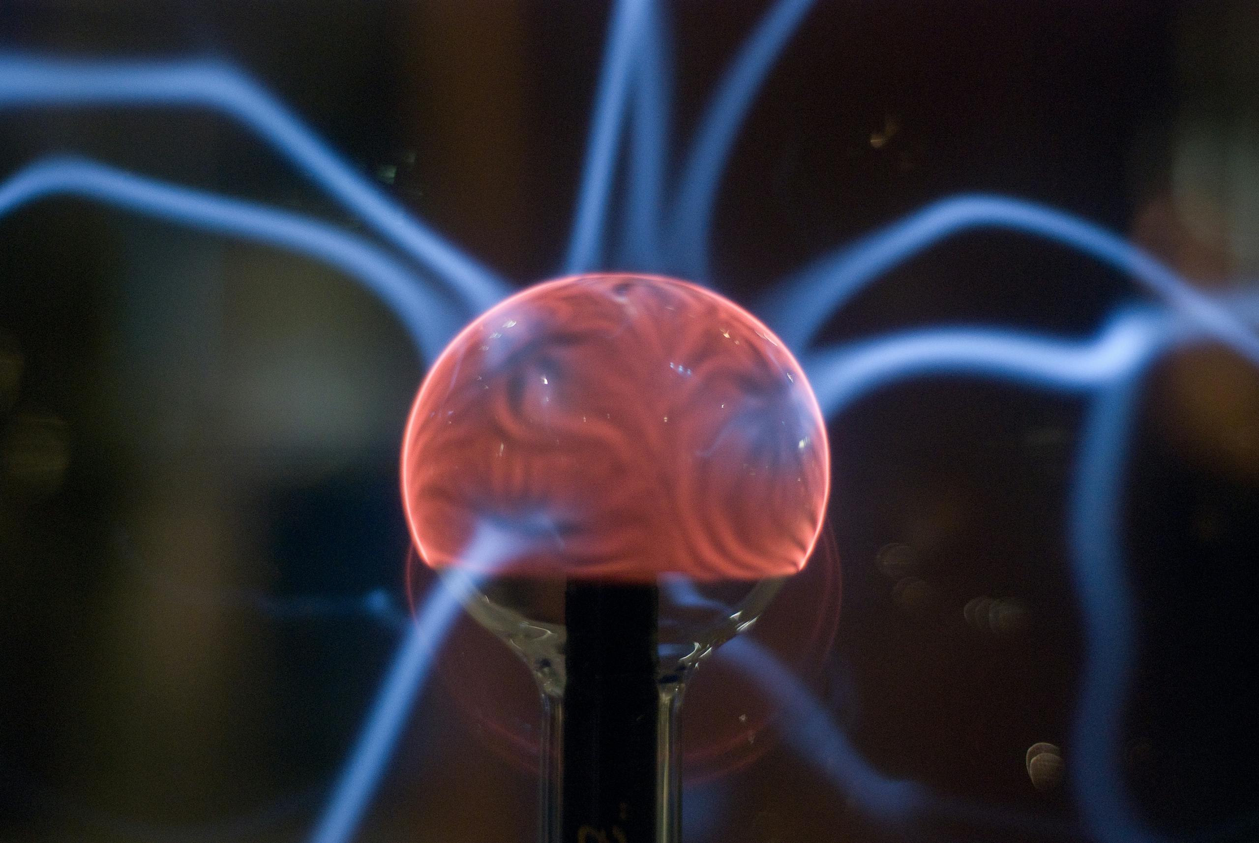 Close-up of glowing plasma ball with electric arcs in darkness.