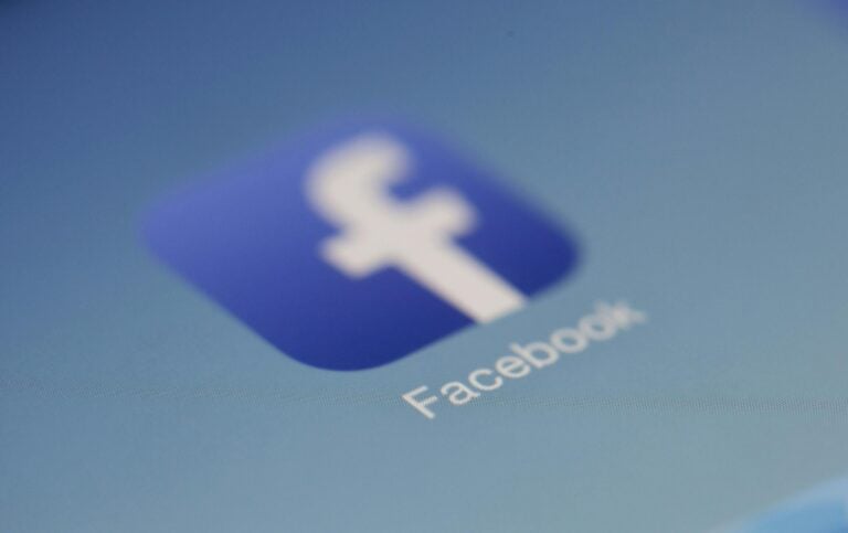 Facebook app logo on digital screen with blurred background closeup.