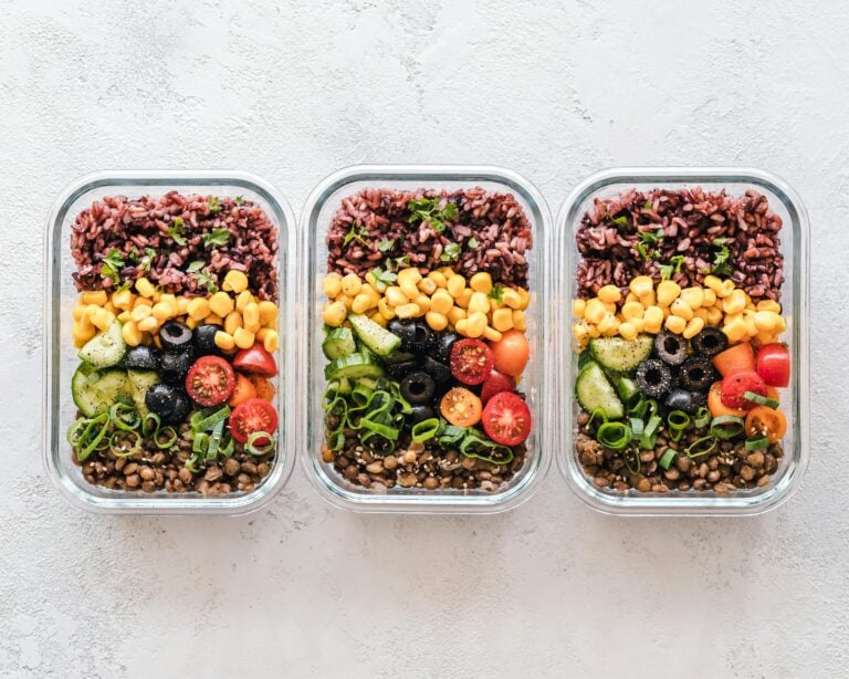Colorful healthy meal prep with corn olives tomatoes and lentils in glass containers