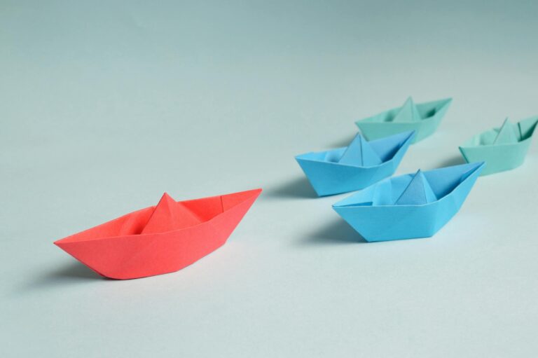 Colorful origami boats arranged depicting leadership and teamwork symbolism