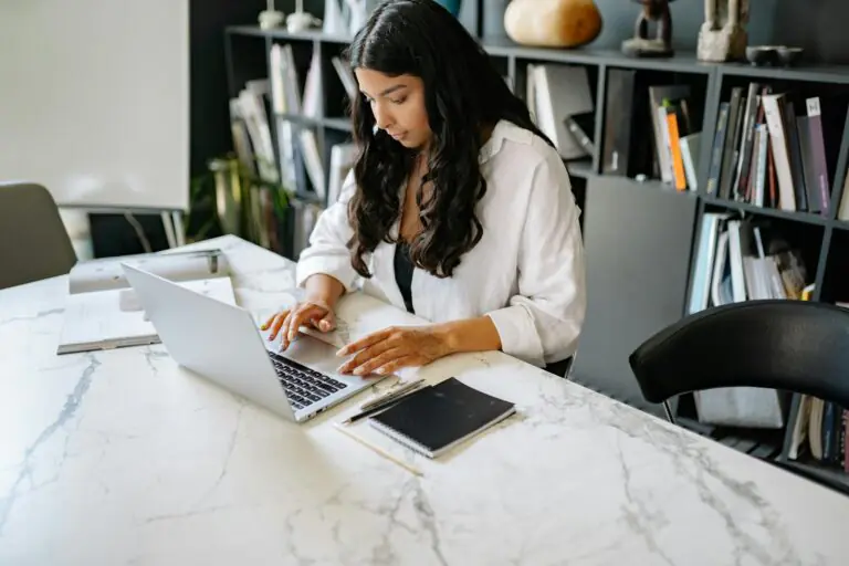 Confident businesswoman working on laptop in modern office setting.